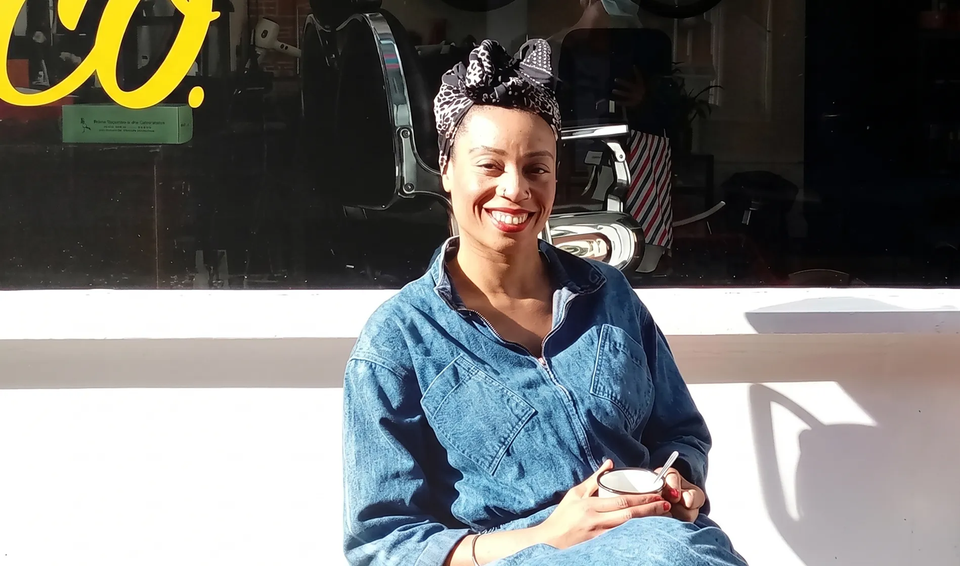 Owner of Levy & Co sits in front of a cafe with a mug of coffee.