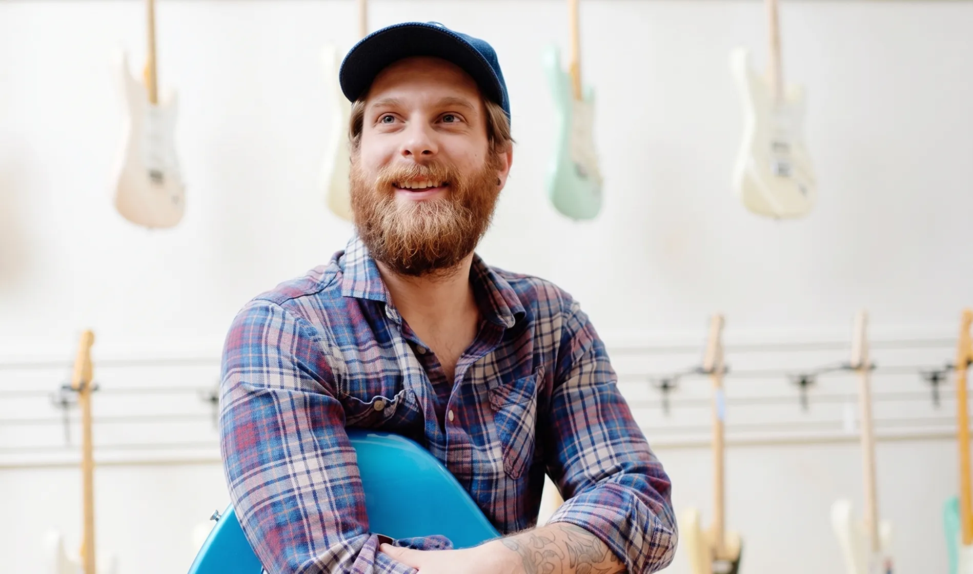 Owner of Chicago Music Exchange looks beyond in front of a wall of guitars.